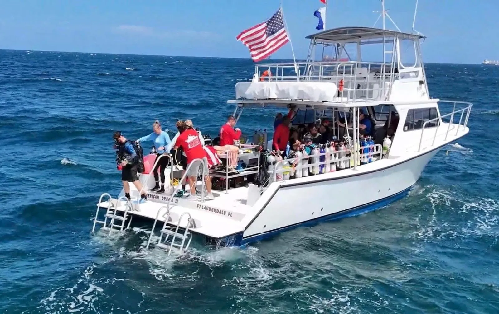 Divers gearing up at the stern of a dive boat flying the American flag